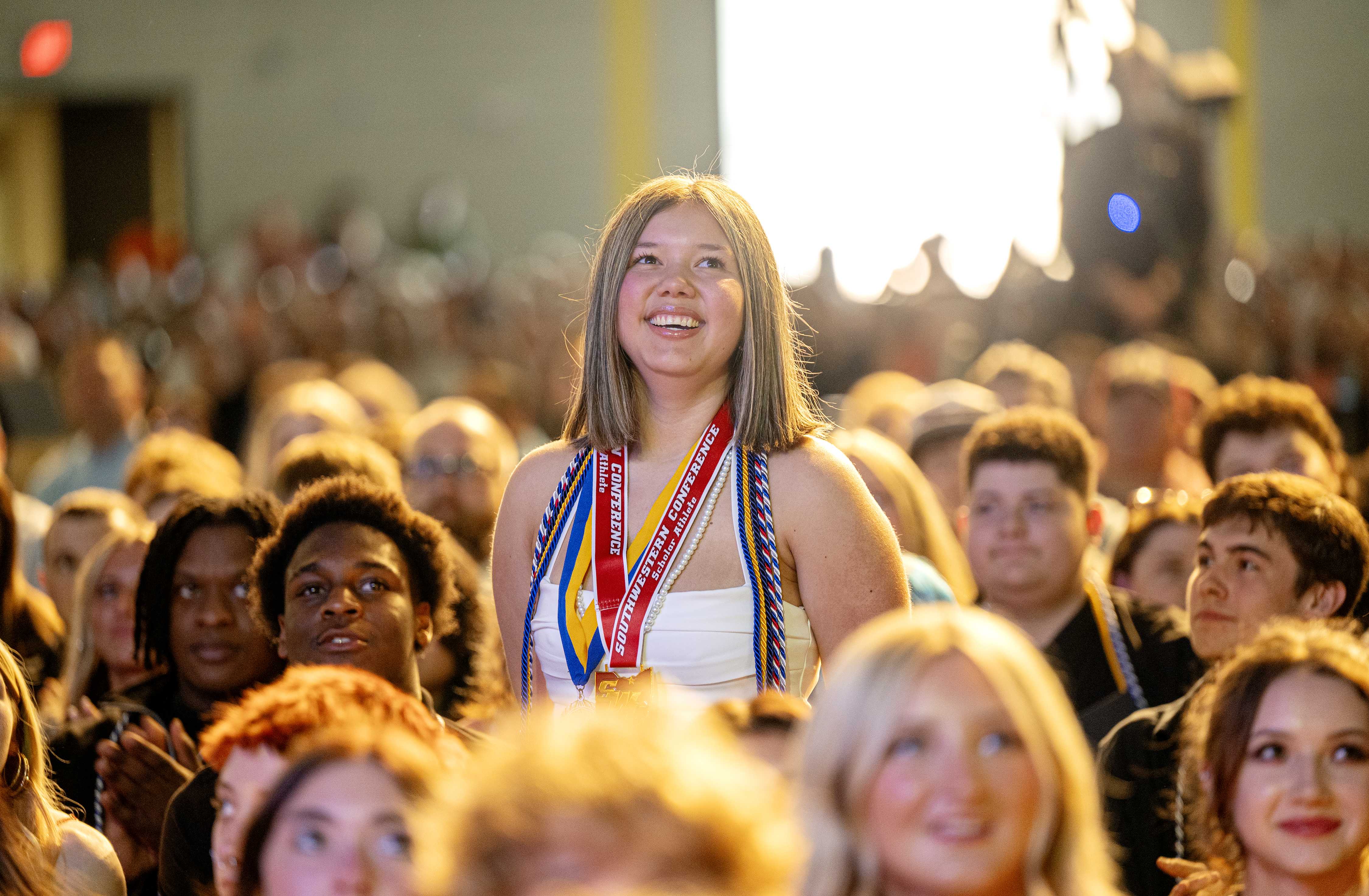 Female student stands up in crowd smiling